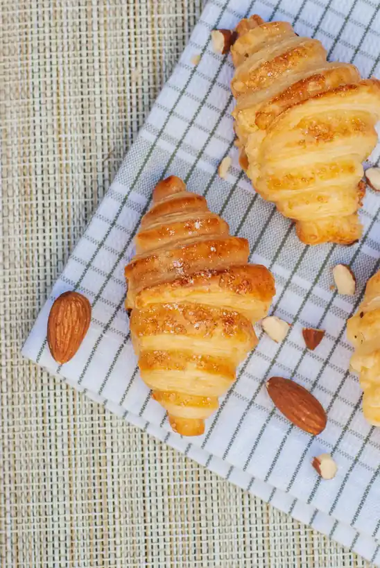 Golden flaky croissants garnished with sliced almonds
