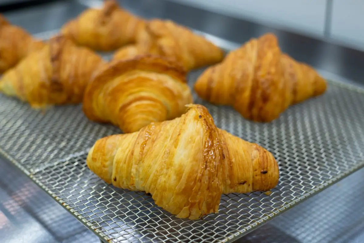 Freshly baked golden butter croissants on a cooling wire showcasing delicate flaky layers