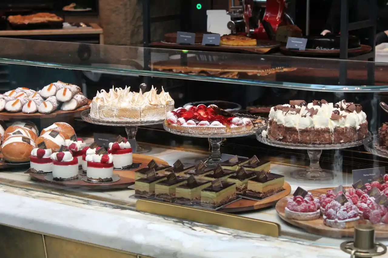 Artisan cakes and handcrafted pastries displayed in an elegant glass patisserie cabinet