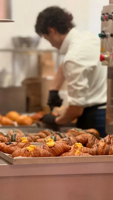 Pastry chef carefully inspecting freshly baked golden pastries on cooling racks in the kitchen