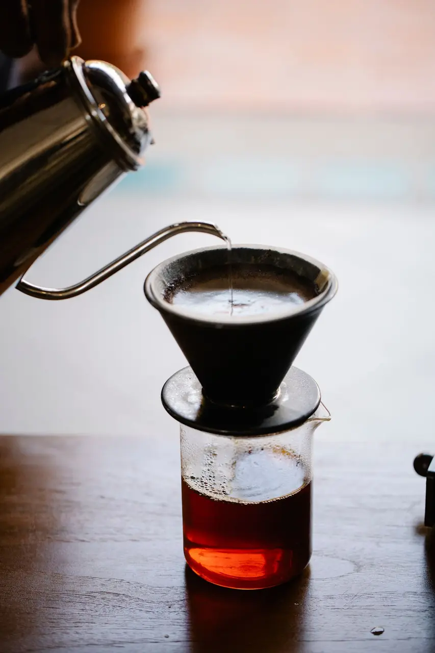 Barista brewing artisan single origin pour over coffee in a clear glass vessel